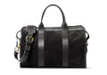 Black suede duffel bag with black leather handles, brass buckle and adjustable shoulder strap, front view