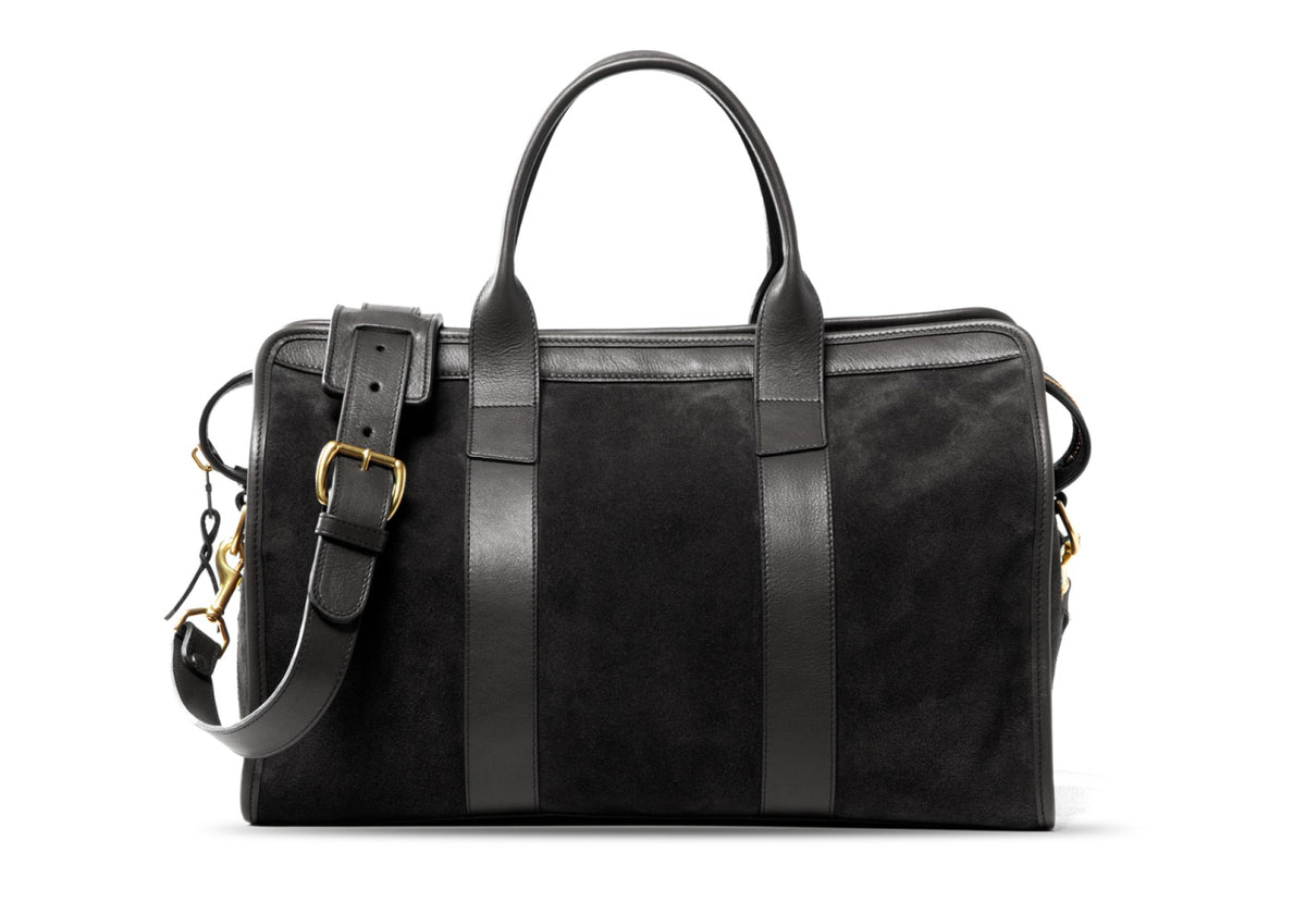 Black suede duffel bag with black leather handles, brass buckle and adjustable shoulder strap, front view