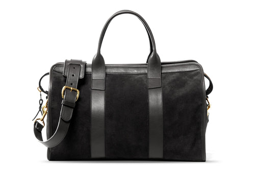 Black suede duffel bag with black leather handles, brass buckle and adjustable shoulder strap, front view
