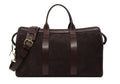 Dark brown suede duffel bag with leather handles, brass buckle and shoulder strap, front view